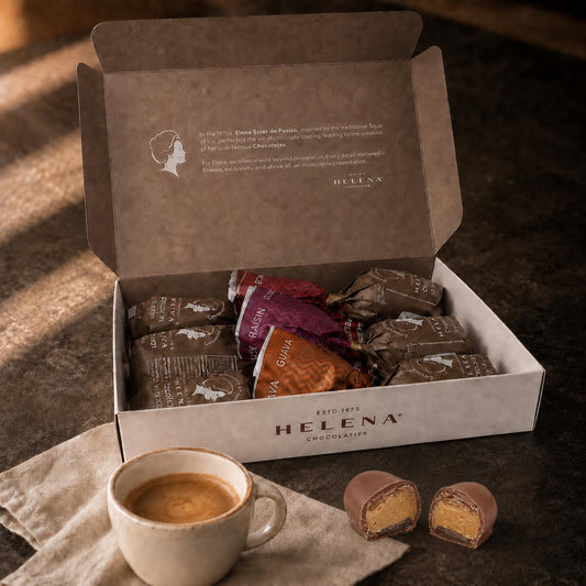 Open Helena Chocolatier gift box with 6 assorted Chocoteja Bonbons in raisin, guava and pecan wrappers, with a cut bonbon showing filling, alongside an espresso cup