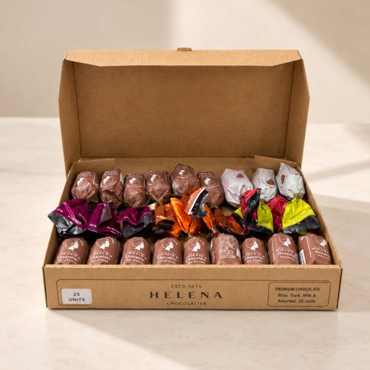 An open cardboard box of Helena Chocolateries containing 25 assorted premium chocolates, with some unwrapped to show milk chocolate and colorful foil wrappers, set on a light beige surface.