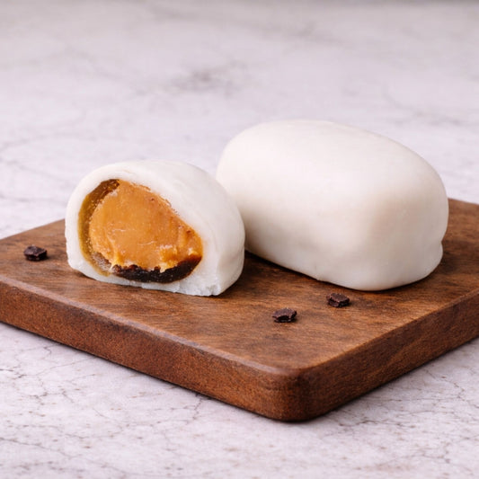  Lemon Teja Bonbon whole and cut in half showing lemon fondant filling on a wooden board