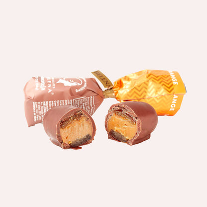 Orange chocoteja bonbon whole and cut in half showing dulce de leche filling with candied orange peel"