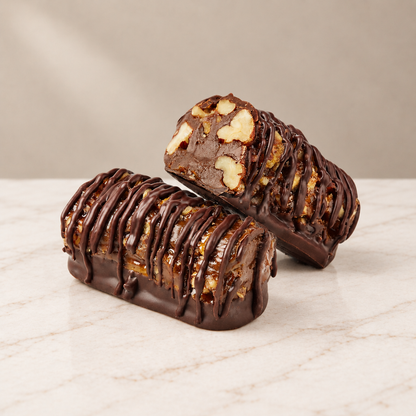 Pecanroll chocolate-covered pecan toffee, cut open to reveal the filling, on white marble.