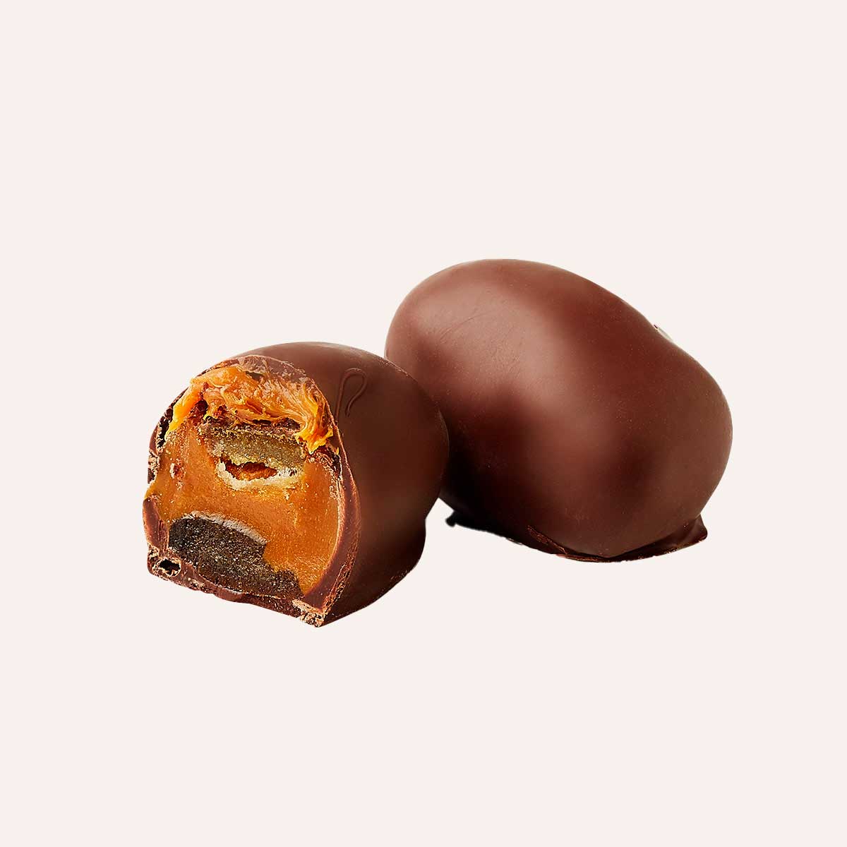 Orange chocoteja bonbon bite revealing smooth dulce de leche and candied orange center